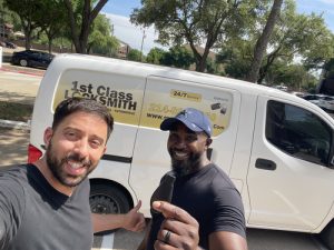 1st Class Locksmith Denton technician smiling with a happy customer after a locksmith service, with a marked van in the background.